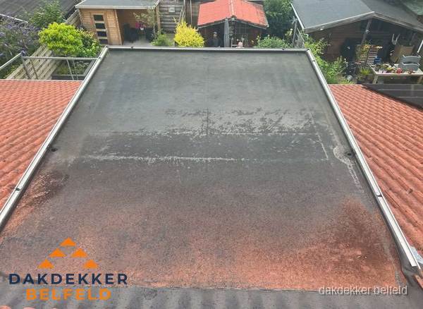 Verouderd plat dak met slijtage tussen schuine daken in Belfeld