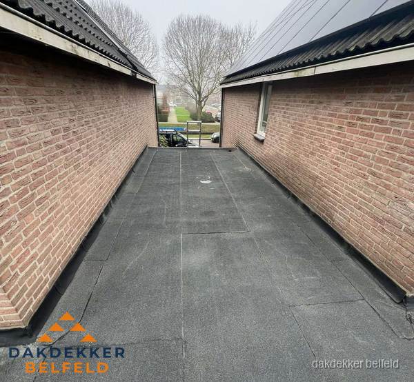Plat dak met bitumen dakbedekking tussen bakstenen muren in Belfeld Plat dak met bitumen dakbedekking tussen bakstenen muren in Belfeld